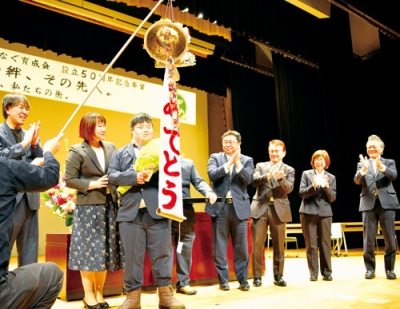 写真：人生の節目を祝ってくす玉を割る高階さん（左から３人目）