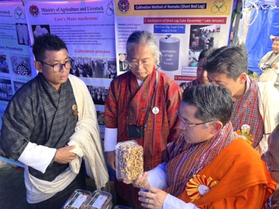 写真：ブータンの閣僚（手前）にナメコの試作商品を説明する熊田淳さん（左から２人目）＝２０２４年８月、ブータン・中部ウラ（国立キノコセンター提供、共同）