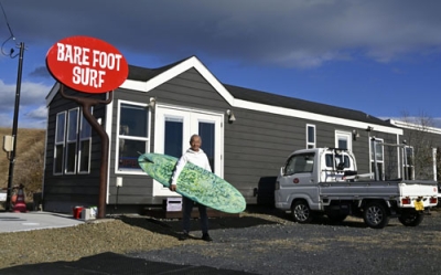 写真：「ベアフットサーフ」の前に立つ越後一雄さん＝２０２５年１２月、宮城県亘理町