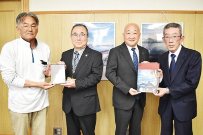 写真:発足20年を記念して制作した記念誌を町役場に贈るかつぐ会の堀家会長(右端)と会計の小林さん(左端)