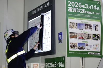 写真:旧運賃表を剥がす作業員。値上げが反映された運賃表が現れた=14日未明、JR東京駅