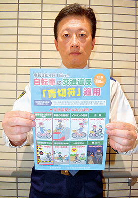 写真：自転車の青切符制度を周知するチラシを手にする室蘭署員