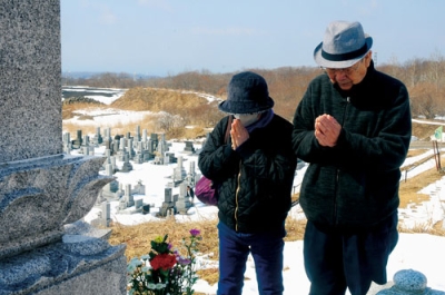 写真：墓前で手を合わせる市民＝１７日午前１０時４５分、室蘭市望洋台霊園