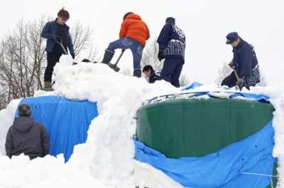 写真：雪山からタンクを掘り出す高砂酒造の社員ら＝１９日午前、美瑛町
