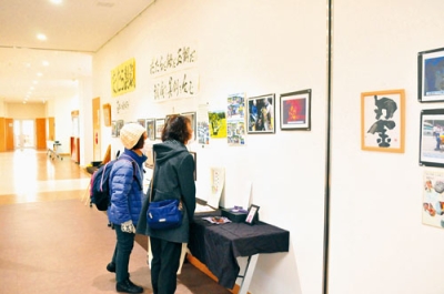 写真：「たたらの会」の活動を紹介する写真に見入る来場者