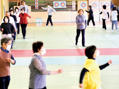 写真：講師の越谷さん（中央）の動きに合わせウオーキングする参加者